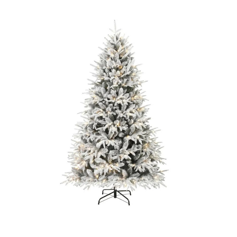 Fyllig snöflockad julgran med ljus