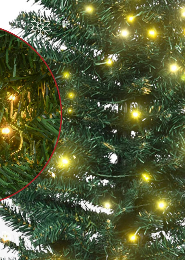 Smal grön julgran med varmvita ljus