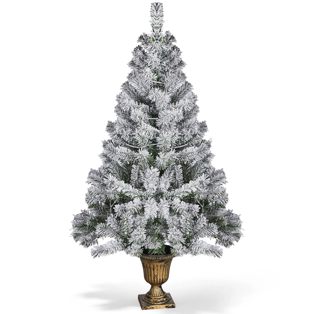 Snöflockad julgran i kruka med ljus