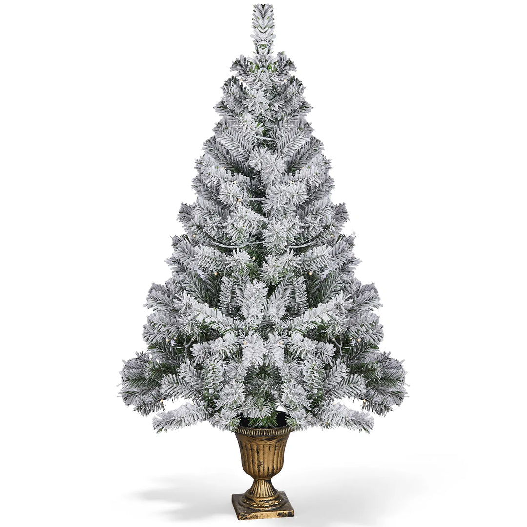 Snöflockad julgran i kruka med ljus