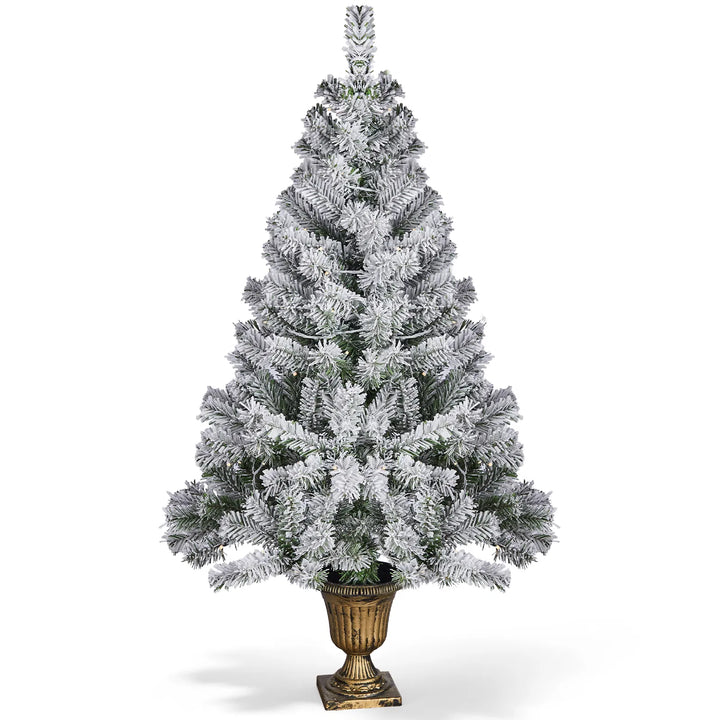 Snöflockad julgran i kruka med ljus